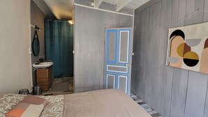 Un dormitorio con cama, un baño con lavamanos y una puerta que da a otra habitación.