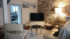 Una sala de estar con pared de piedra, televisor, sofá y mesa.