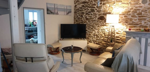 A living room with a stone wall, a television, a sofa, and a table.