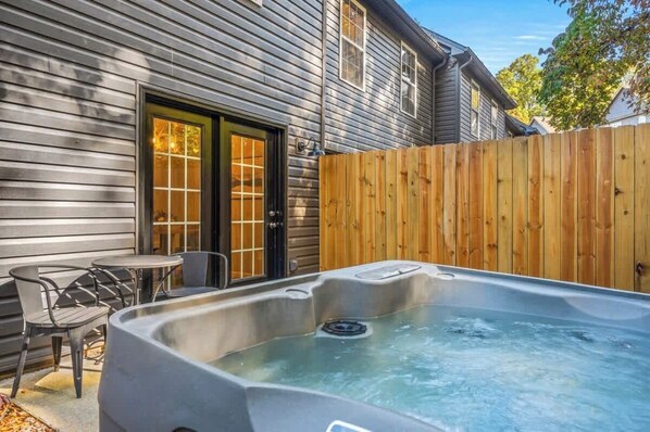 A hot tub in a backyard with a wooden fence, a door, and a small table with chairs. - Peaceful Stay Awaits, Sleeps 6・Hot tub・Arcade (Sevierville)