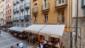 Une vue de niveau de la rue d’un restaurant doté d’une terrasse, d’un auvent blanc et d’une façade en pierre.
