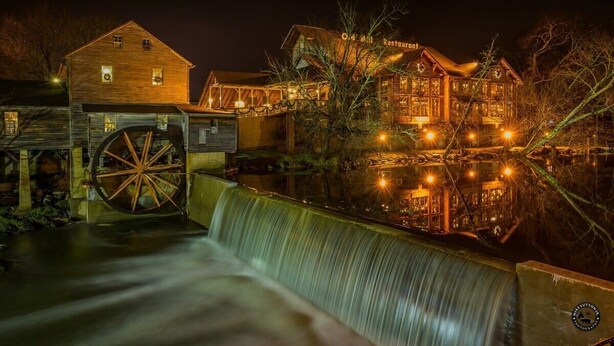 A historic building with a water wheel and a restaurant sign.