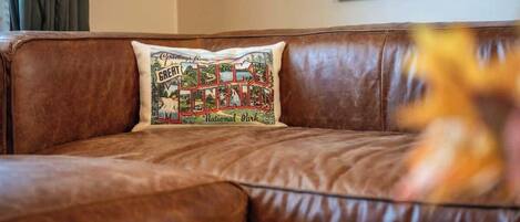 A brown leather sofa with a cushion featuring a vintage-style design.