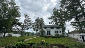 A two-story house with a front porch, surrounded by a well-maintained lawn and trees.