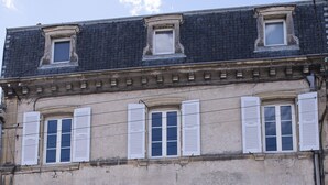 Un edificio de varios pisos con contraventanas blancas en las ventanas, una puerta visible y un letrero con el número 5.