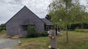 A wooden house with a sloped roof, a small porch, and a wooden deck.