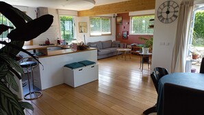 A cozy living area with a kitchen, a sofa, a dining table, and a clock on the wall.