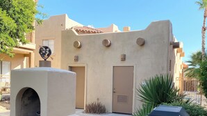 Un bâtiment à la façade beige, avec une porte et un petit espace barbecue extérieur.