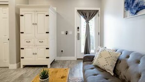 Un salon avec un canapé gris, une table basse en bois ornée d’une plante et un meuble blanc doté de plusieurs portes.