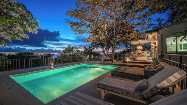 A swimming pool with lounge chairs and a patio area, surrounded by trees and a view of the landscape. - Casa Aves - Gorgeous Ocean & Jungle View 3BR w/ Pool (nosara)