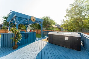 A wooden deck with a hot tub and a pergola with string lights. - Cosmos Stays, Open Space, Jacuzzi, King Beds, Hot Tub, Serene, Spacious (Bolingbrook)