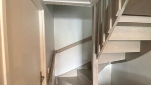 Una escalera con peldaños de madera y barandillas blancas que conduce a un rellano con una puerta.