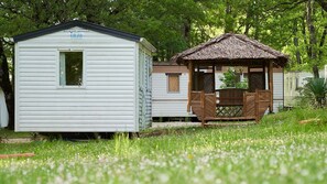 A row of mobile homes with a small wooden structure in the middle.