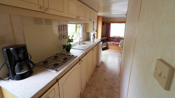 A compact kitchen with a gas stove, a coffee maker, and a sink.