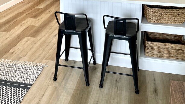 Una cocina moderna con armarios blancos, un refrigerador de acero inoxidable, una isla grande con taburetes de bar y una lámpara colgante.