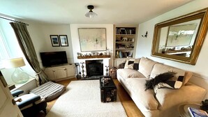 A living room with a sofa, a coffee table, a TV, a fireplace, and a bookshelf.