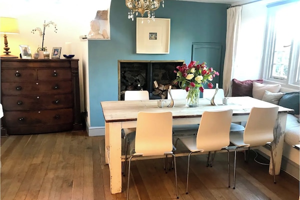Dining room, with large refectory table, woodburner and piano.