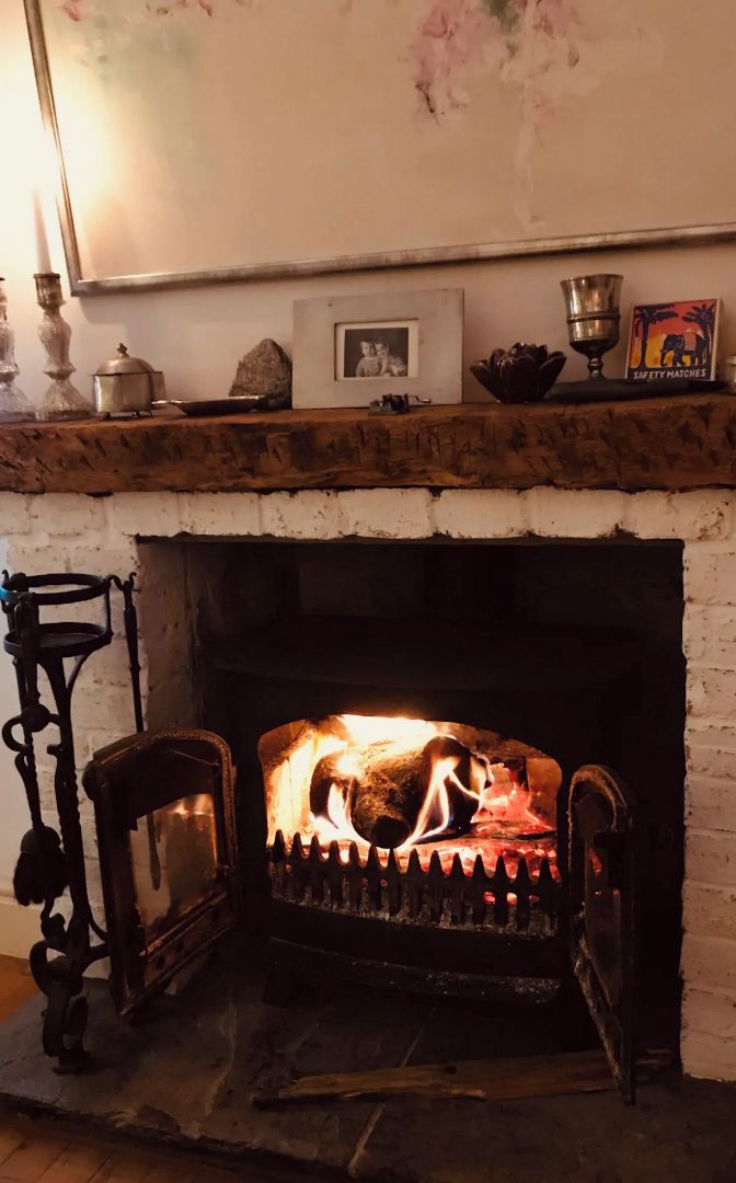 A fireplace with a burning fire, a mantel with various items, and a framed photo above it.