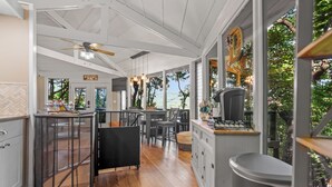 A spacious kitchen with wooden flooring, a bar area, and large windows offering a view of the outdoors. - Treetop Getaway with AMAZING lake views! (Jasper)