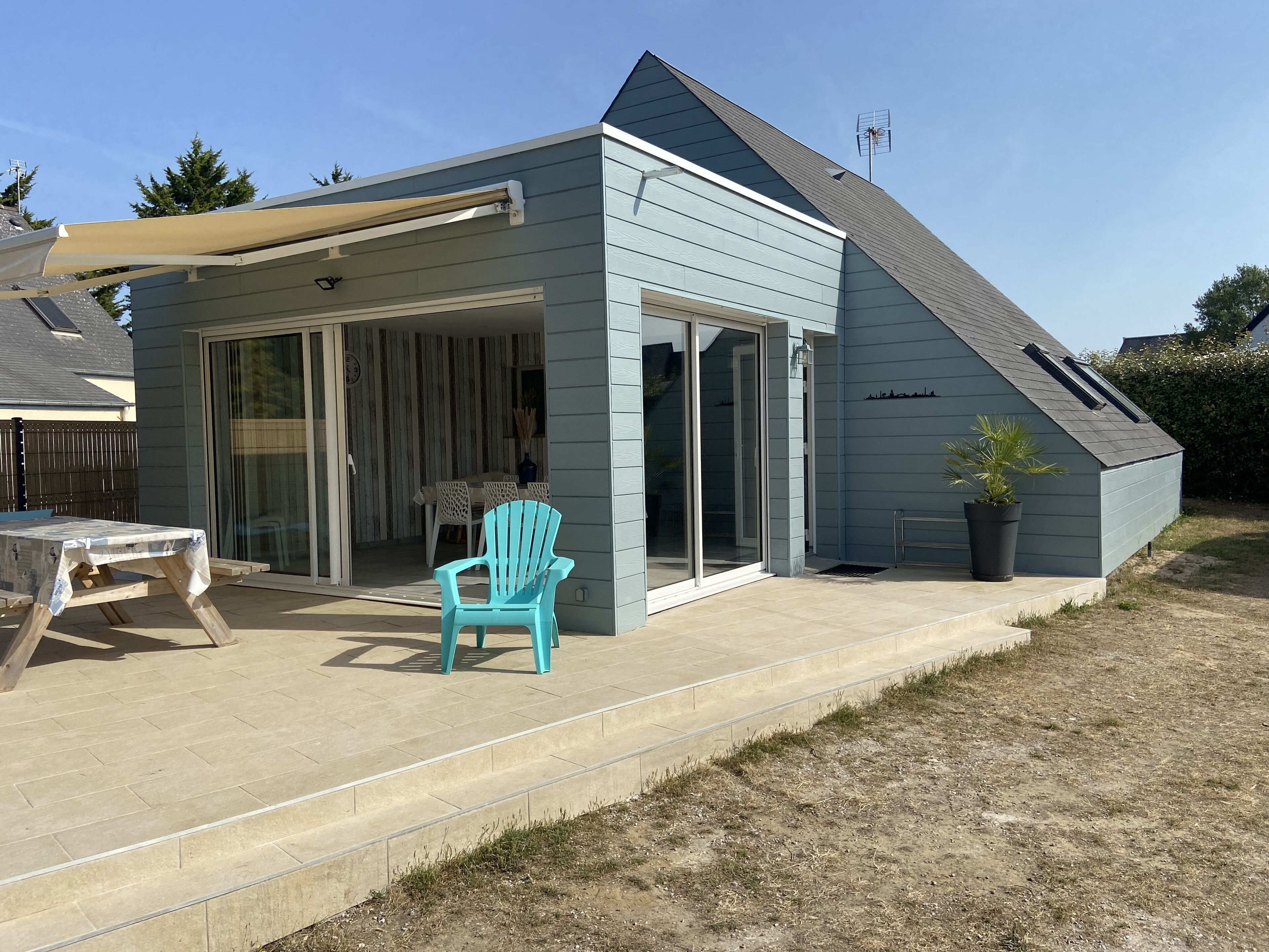A house with a covered patio, a sliding glass door entrance, and a small garden area with a potted plant.