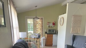 A living room with a sofa, a chair, a dining table, and a kitchen area in the background. - Cute, clean home on big private lot in Inverness FL. (Inverness)