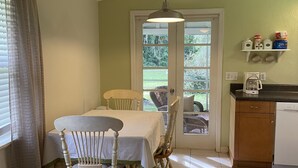 A dining area with a table and chairs, a kitchen with a coffee maker, and a door leading to a balcony. - Cute, clean home on big private lot in Inverness FL. (Inverness)