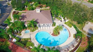 Vista aerea di un resort con una grande piscina, palme e un edificio con tetto.