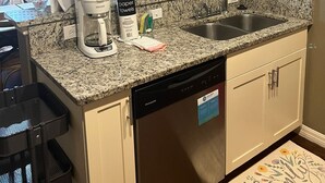Cucina con piani in granito, lavastoviglie, macchina del caffè e quadri appesi al muro.