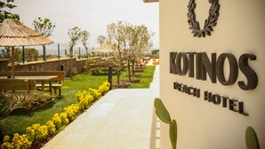 Een pad dat leidt naar het KOTINOS Beach Hotel met terras en uitzicht op de oceaan.
