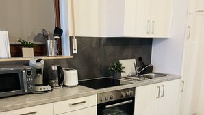 A modern kitchen with white cabinets, a built-in oven, a microwave, and a coffee maker. - Emma vacation apartment on the Romantic Road (Weikersheim)