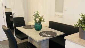 A modern dining area with a marble table, black upholstered chairs, and a green vase with flowers. - Emma vacation apartment on the Romantic Road (Weikersheim)