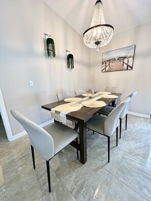 A dining area with a rectangular table, six chairs, a chandelier, and a painting on the wall. - Newly renovated home in a quiet location (Englewood)