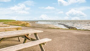 Una mesa de picnic en un camino de grava junto al mar, con olas rompiendo en la orilla.