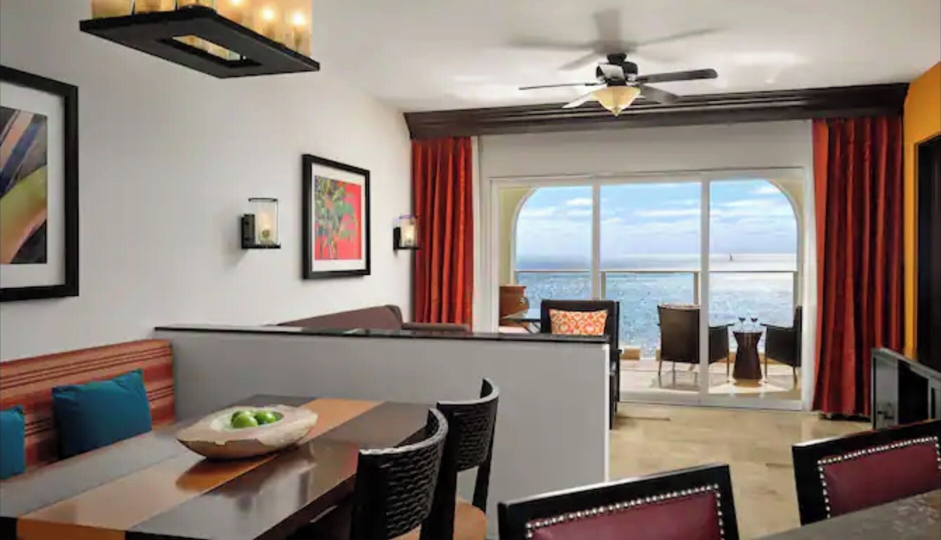 A modern hotel room with a balcony, a dining area, and a view of the sea.