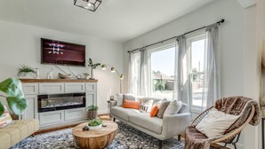 Una sala de estar con chimenea, sofá, mesa de centro y televisor montado en la pared.