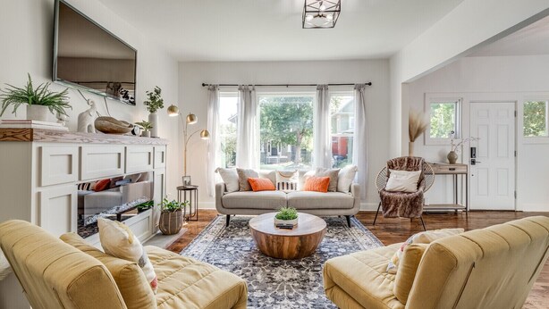 Un salón amplio con sofá, dos sillones, una mesa de centro y televisor montado en la pared.
