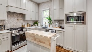 Una cocina moderna con armarios blancos, estufa de acero inoxidable y microondas integrado.