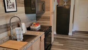 A modern kitchen with wooden cabinets, a granite countertop, a stainless steel sink, a microwave, an oven, and a refrigerator. - Lake front LAWN FLOOR of bi-level home.
 bottom floor only. private entrance. (Dorena)