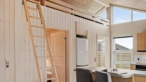 A modern kitchen with wooden paneling, a built-in refrigerator, and a window overlooking a residential area.