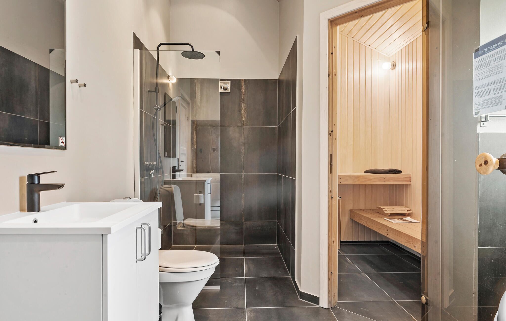 Et moderne badeværelse med en hvid vask, toilet og bruseniche.