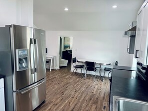 Una cocina moderna con electrodomésticos de acero inoxidable, dispensador de agua y zona de comedor con mesa y sillas.