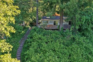 A house surrounded by dense greenery, with a visible deck and a pathway leading to the entrance. - Heron House - Hot Tub and Wine Tastings Included (Healdsburg)