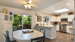A kitchen with white cabinets, a central island, and a dining area with blue chairs.