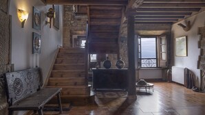 A rustic interior with a wooden staircase, a bench, and a view through a window.