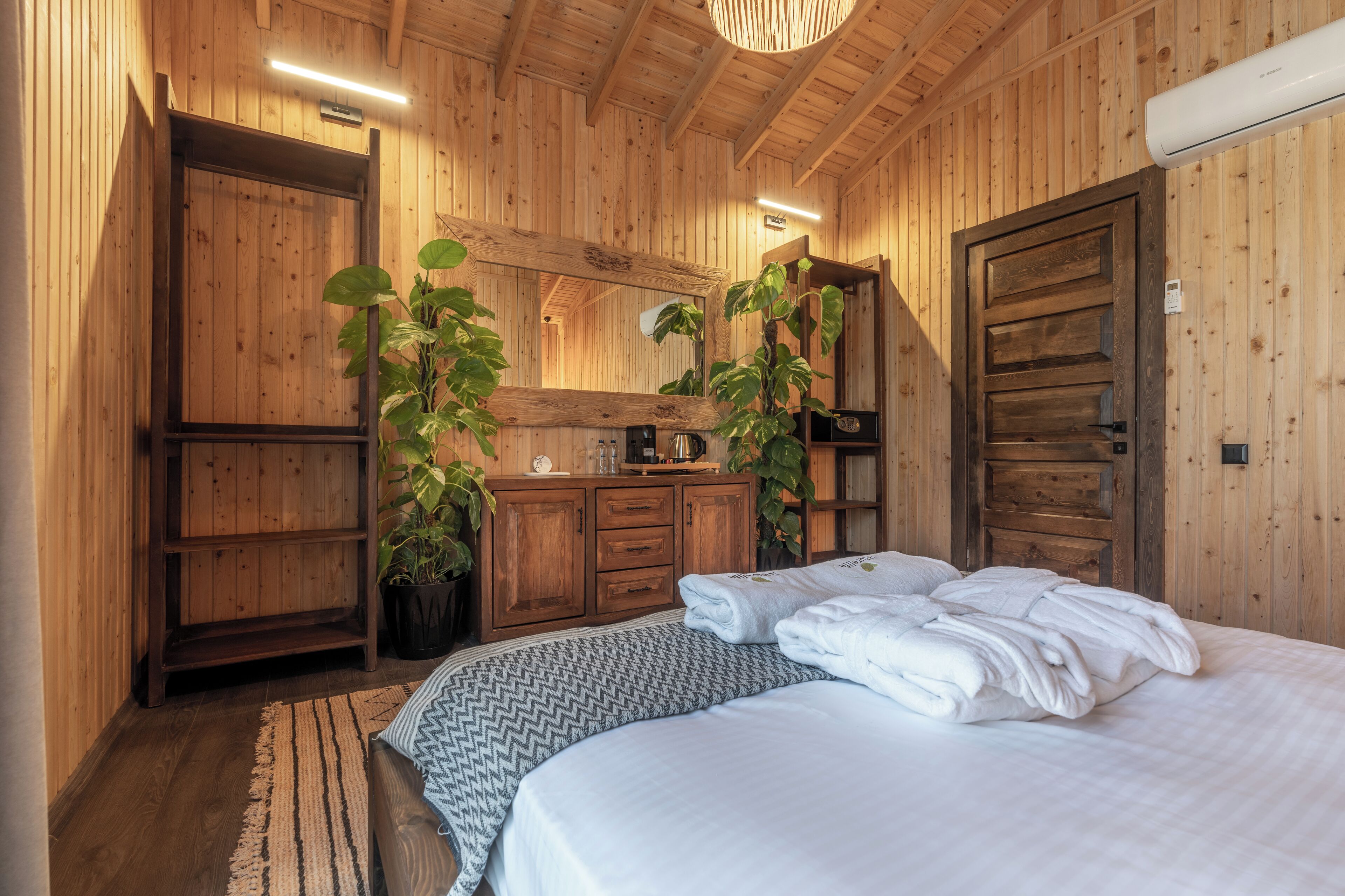 Una habitación de madera con una cama, un aparador y dos macetas.