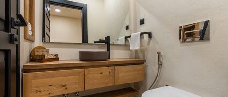 Un baño moderno con tocador de madera, un espejo grande, inodoro blanco y perchero.