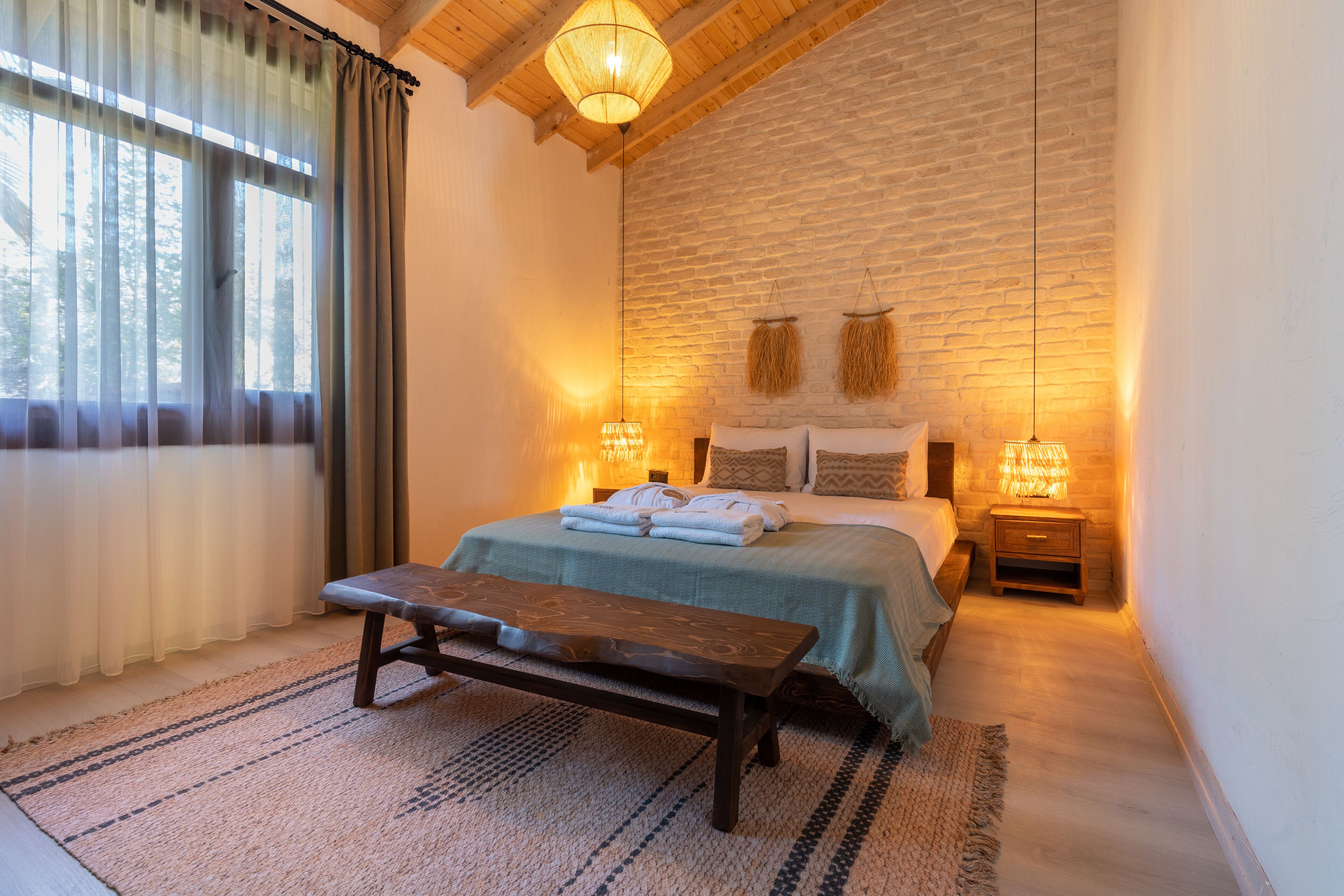 A cozy bedroom with a large bed, a wooden bench, and two bedside lamps.
