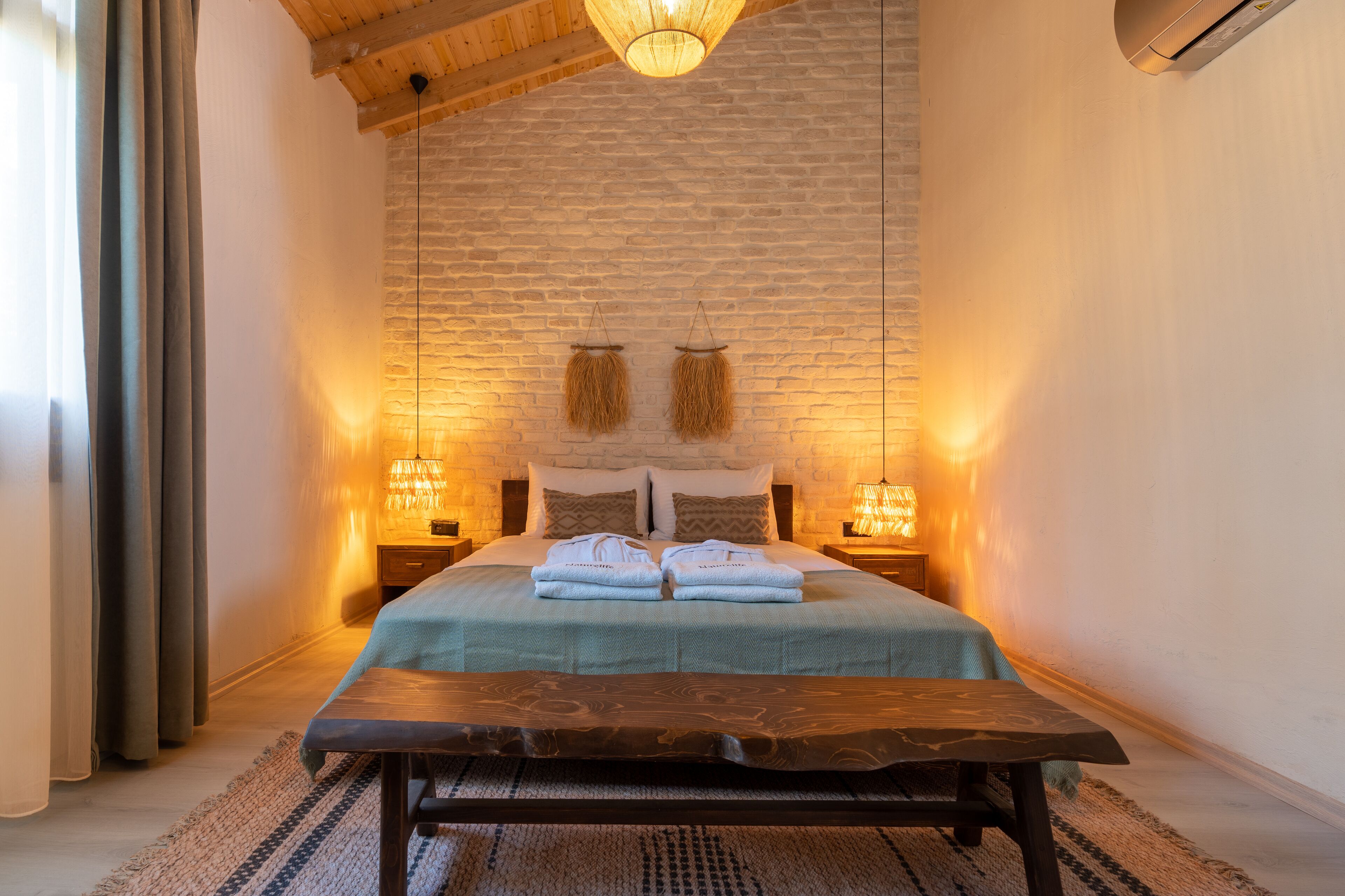 A cozy bedroom with a large bed, two bedside lamps, a wooden headboard, and a hanging light fixture.