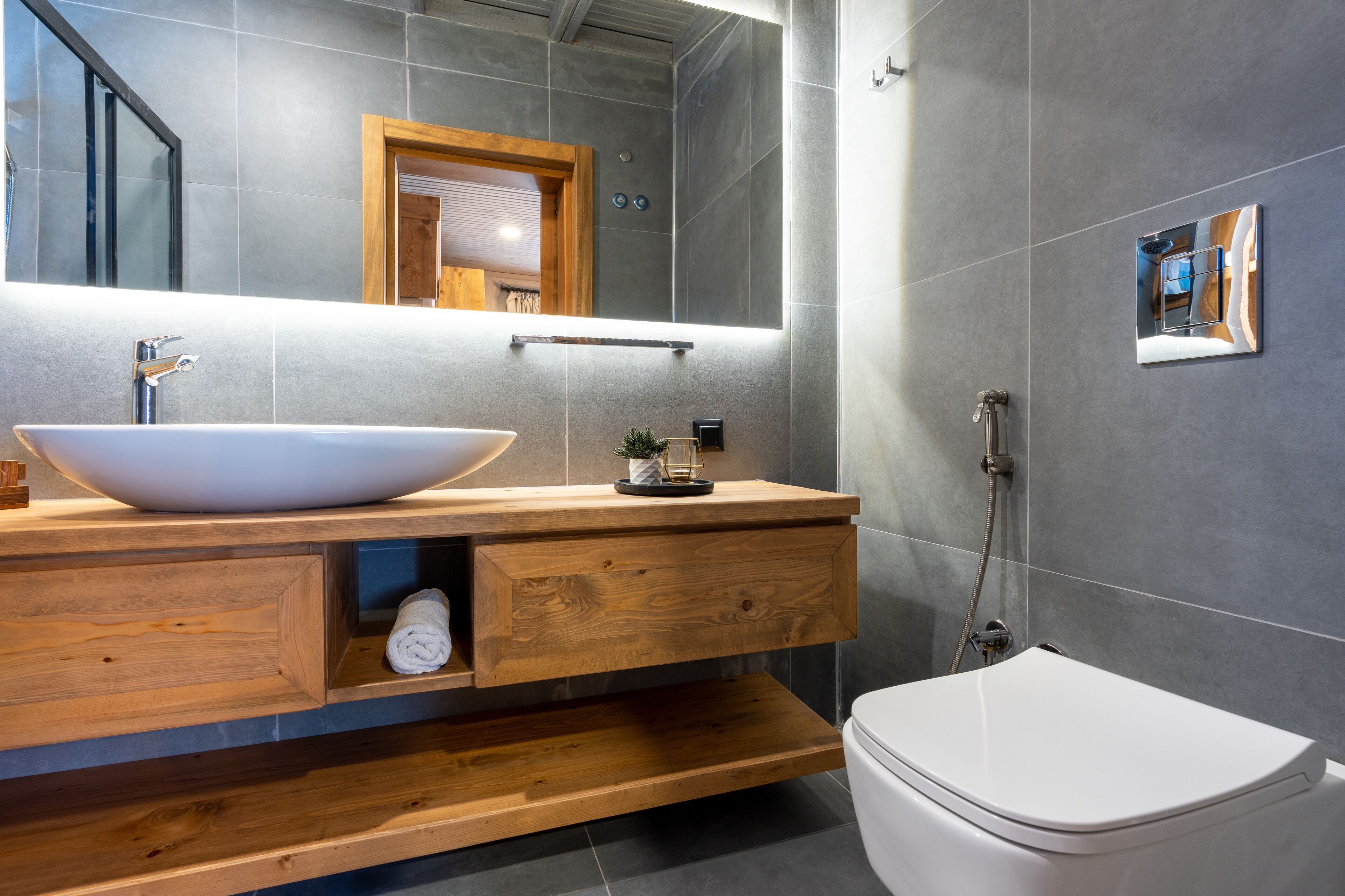 Ein modernes Badezimmer mit einem großzügigen Aufsatzwaschbecken, einem Holzausziehtisch und einer Toilette.