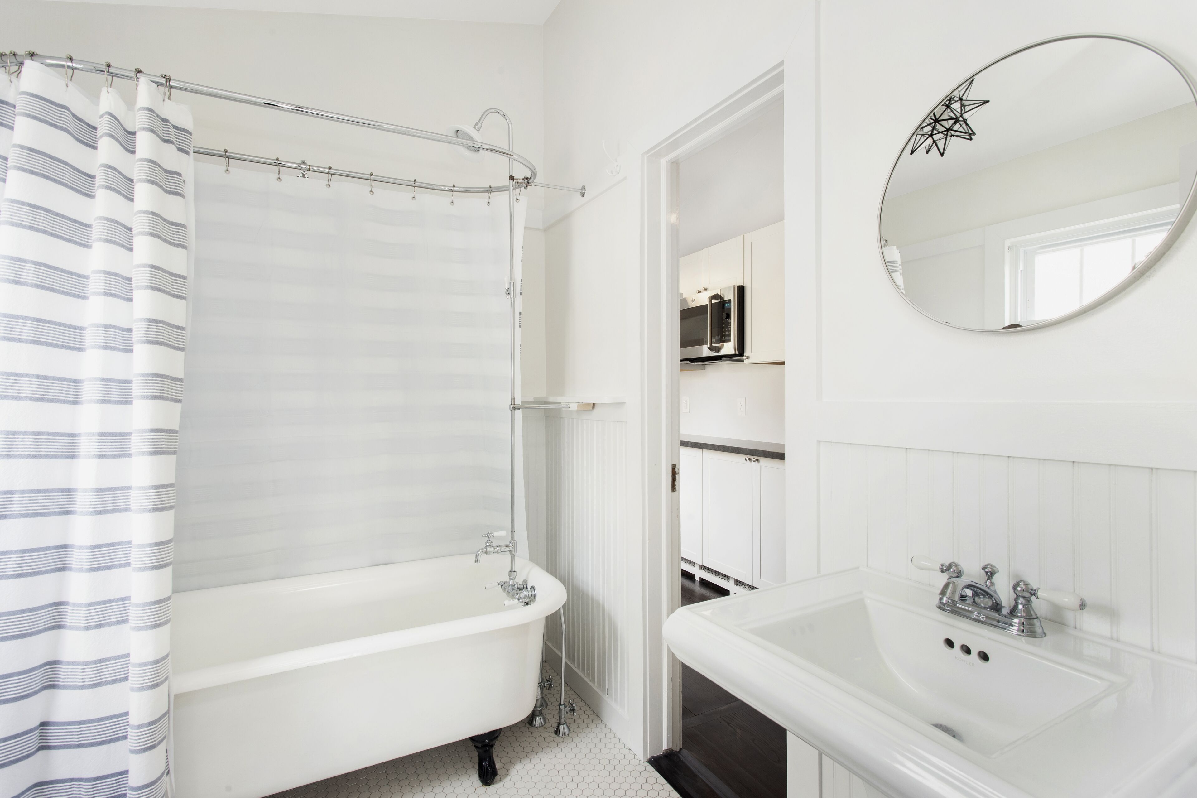 Ein modernes Badezimmer mit einer freistehenden Badewanne, einem Waschbecken und einem Spiegel.
